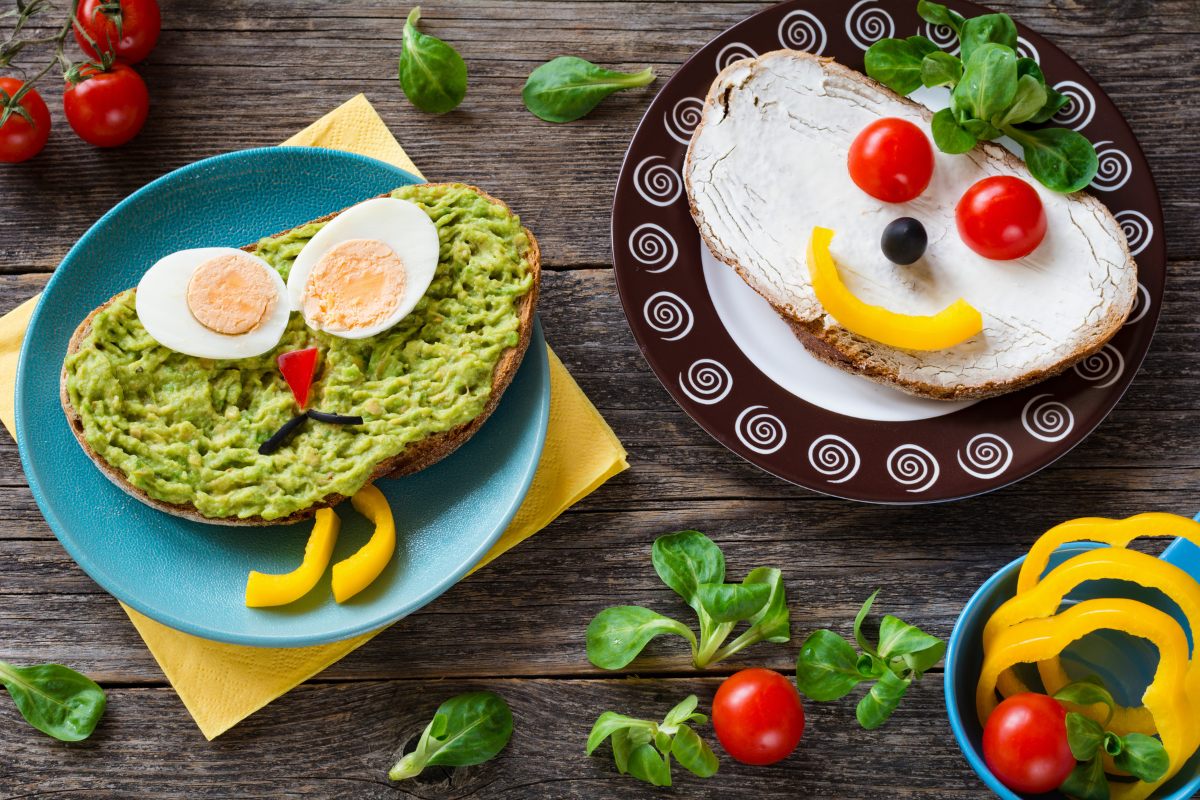 Two open sandwiches for kids, one with mashed avocado and hard boiled egg and other with cream cheese and vegies.
